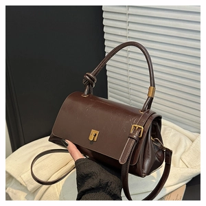 Detailed shot of dark brown oil wax leather bag with vintage gold clasp and knot handle