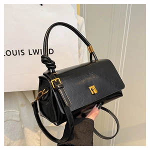 Detail of black soft leather handbag featuring golden twist-lock and knotted handle detail