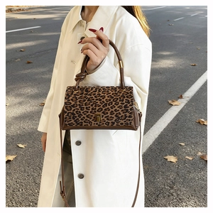 Close-up of leopard print handbag with golden buckle worn with a beige trench coat