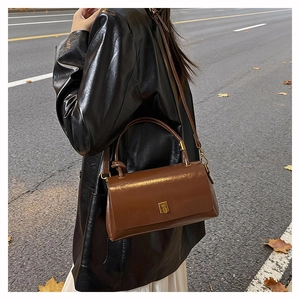 Dettaglio di borsa in pelle marrone con fibbia dorata e accenti animalier leopardati