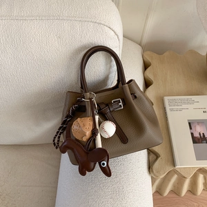 Dunkelbraune Handtasche aus Leder mit Litschi-Muster, Lederhund-Anhänger und Baseball-Deko