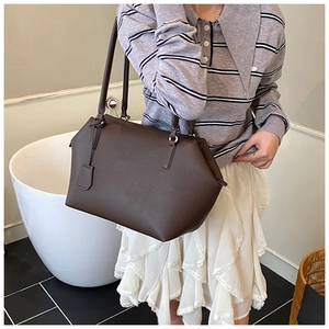 Detail of deep brown litchi pattern shoulder bag with a stylish matching charm