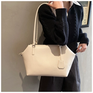 Close-up of minimalist off-white lychee grain leather tote bag worn by a model