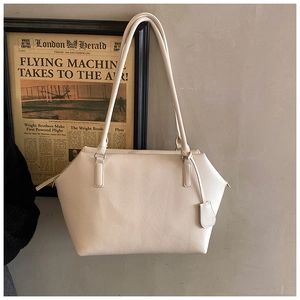Detail of cream leather tote bag featuring rich lychee texture and sturdy shoulder straps