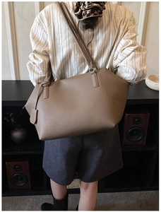 Detailed close-up of brown tote bag showing litchi grain texture and long shoulder strap