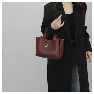 Detail of wine red lychee grain leather bucket bag with silver metal ring and T-stamp