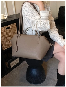 Detailed side view of earth-tone leather tote bag with shoulder straps and pebble texture