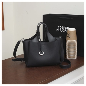 Detail of black lychee grain leather handbag with metal ring and branded packaging