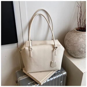 Detailed macro view of off-white lychee grain leather tote with premium texture