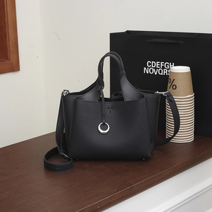 Close-up of black lychee grain leather bucket bag with silver ring detail and T-stitch