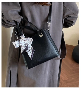 Detail of black pebbled leather tote bag featuring a decorative marble pattern silk scarf