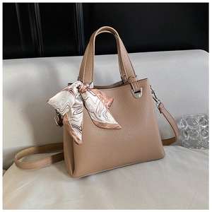 Detail of beige faux leather handbag with litchi texture and elegant printed scarf handle