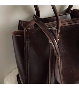 Detail of dark brown tote bag showing glossy leather texture and fine stitching