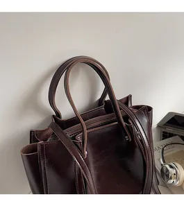 Close-up of the smooth shoulder strap and stitching on the dark brown tote bag