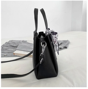 Side view of black lychee grain leather tote bag with silk scarf on handle and silver hardware
