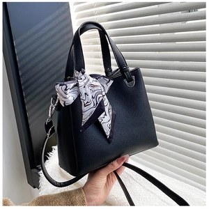 Close-up of black lychee grain leather tote bag with printed silk scarf and silver hardware