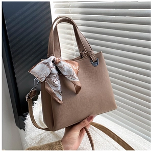 Detail of light brown crossbody bag featuring lychee texture leather and marble silk scarf