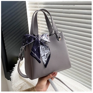 Detailed macro view of gray lychee leather texture and silver hardware with scarf accent