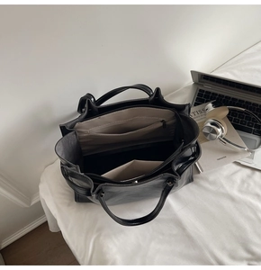 Close-up of black tote bag interior showing multiple compartments and zip pockets