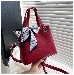 Detail of dark red lychee texture leather handbag with silk scarf handle and silver hardware