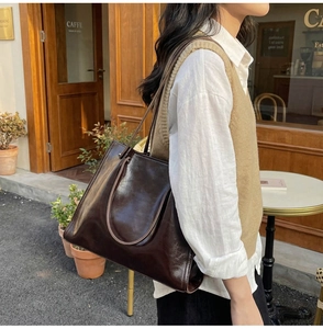 Outdoor shot of a vintage dark brown tote bag in glossy leather with slim shoulder straps