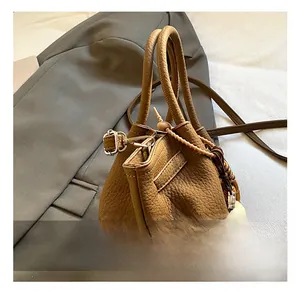 Close-up of brown litchi grain leather bag with vintage tassel and bead charms