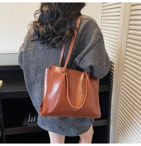 Minimalist brown large capacity tote bag shown being worn over the shoulder in a lifestyle setting