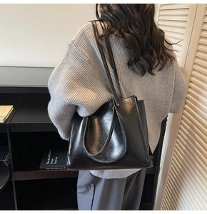 Detailed view of black faux leather tote bag with long shoulder straps for underarm wear