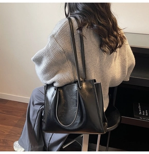Detail view of glossy oil wax leather texture on the black tote bag with handle straps