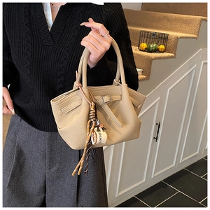 Close-up of beige lychee grain leather handbag with coffee cup charm detail