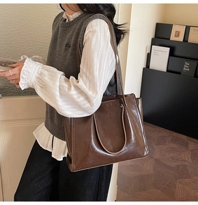 Detail of dark brown leather tote bag showing smooth glossy texture and precise stitching