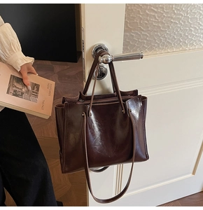 Detailed view of dark brown tote bag hanging on a door handle in an aesthetic setting