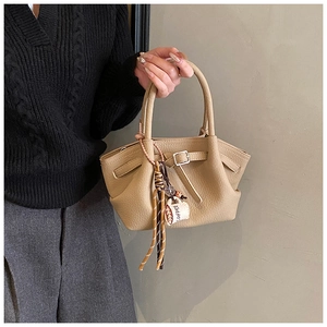 Detail of light brown lychee grain leather handbag with stylish coffee cup bag charm