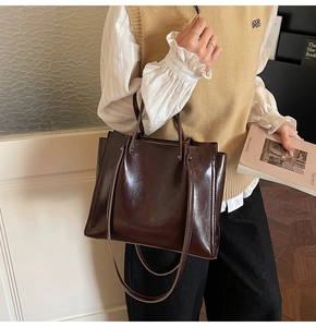 Detail of dark brown glossy leather tote bag with long handles for daily commuting