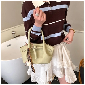 Detail of pistachio green leather handbag with unique coffee cup charm and metal buckle