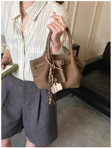 Detailed shot of brown litchi pattern handbag with stylish COFFEE pendant and tassel