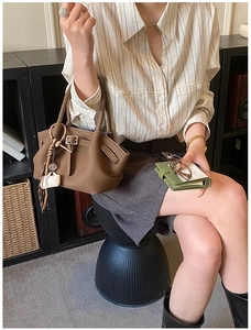 Close-up of brown litchi grain leather handbag with creative coffee cup charm detail