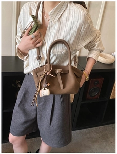 Detail of dark brown leather crossbody bag with pleated texture and coffee charm