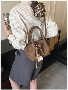 Detail view of brown pebbled leather tote bag with coffee charm and adjustable strap