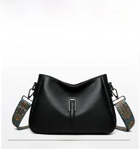Détail d'un sac à main en cuir grainé noir avec une bandoulière bohème colorée large