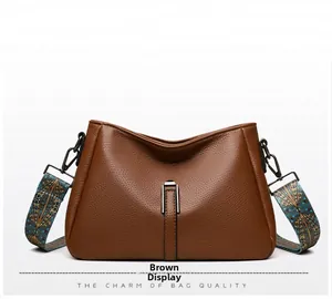 Détail du sac en cuir marron grainé avec bandoulière large tissée de style bohème