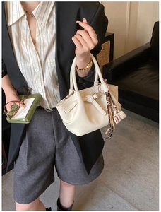 Chic beige lychee grain handbag with trendy coffee charm shown in a modern lifestyle outfit