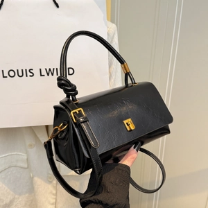 Fashionable black faux leather handbag with unique knotted handle and gold metal buckle