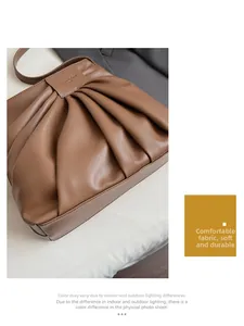 Detail of brown pleated leather texture and logo plaque on a retro underarm bag
