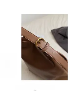 Detailed close-up of brown leather bag with vintage gold buckle and strap adjustment
