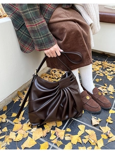 Detail view of the deep brown pleated texture and leather tag on a vintage shoulder bag