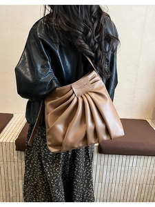 Detail of tan ruched shoulder bag showing textured faux leather and embossed logo patch
