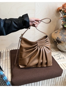 Detail of dark brown pleated leather shoulder bag with chic accordion fold design