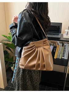 Close-up of brown pleated shoulder bag with retro vertical texture and fashion label