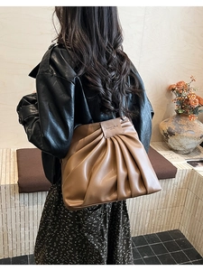 Detail of coffee leather shoulder bag featuring retro pleats and embossed fashion label